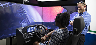 A female student and instructor operate the driving simulator at Craven Community College