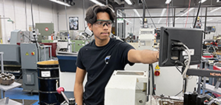 A male student at Johnson Community College calibrates the programing in the machine shop.