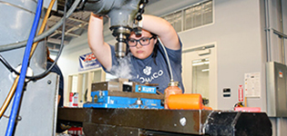 Female student uses industry drill in the lab.