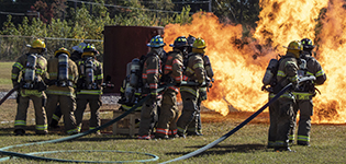 Students practice fire fighting techniques in putting out external flames.